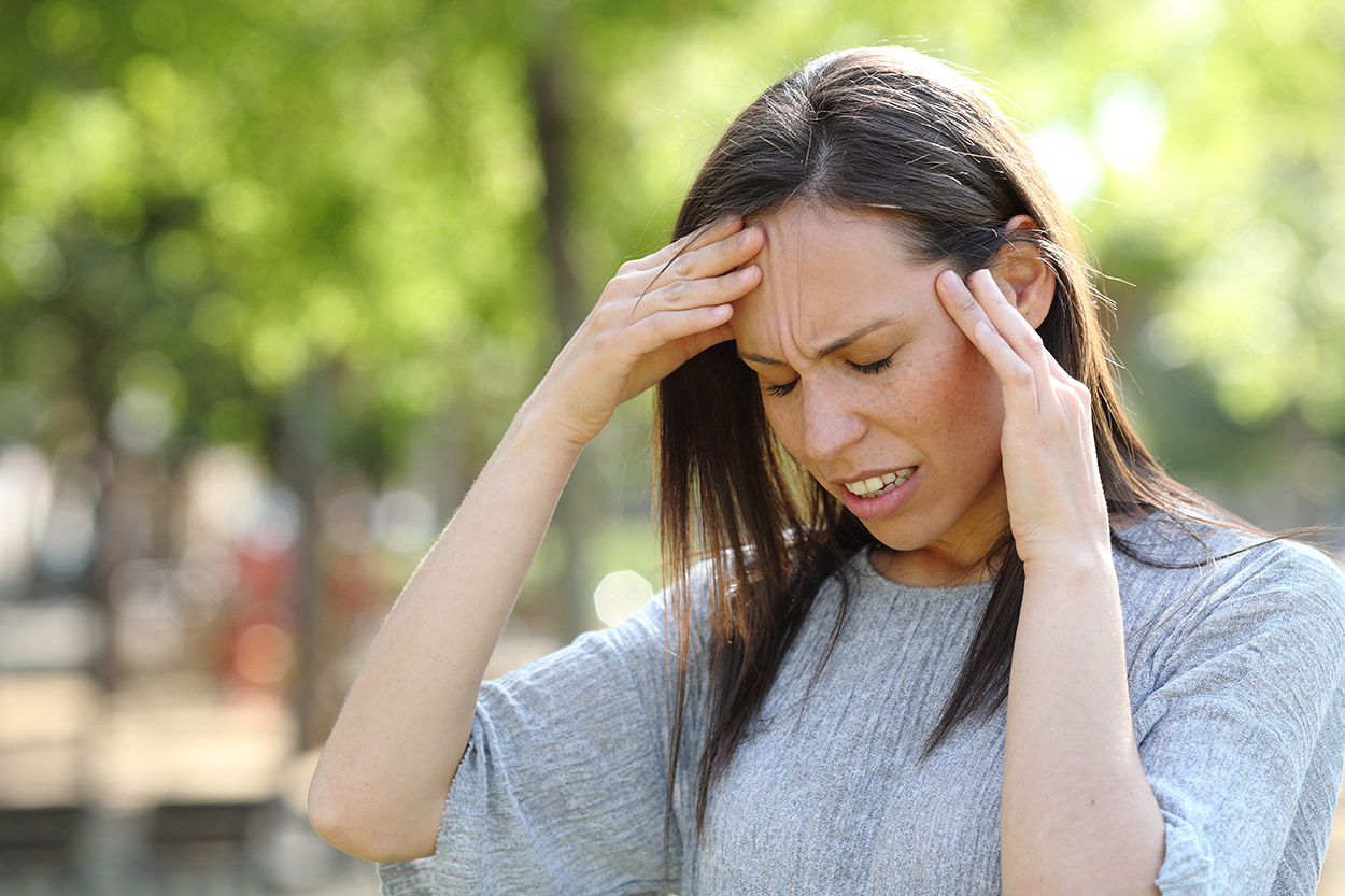 Woman having a migraine outside